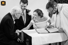 Bride reaching for her grandfather’s hand during the signing of the register at Houghton on the Hill Church.